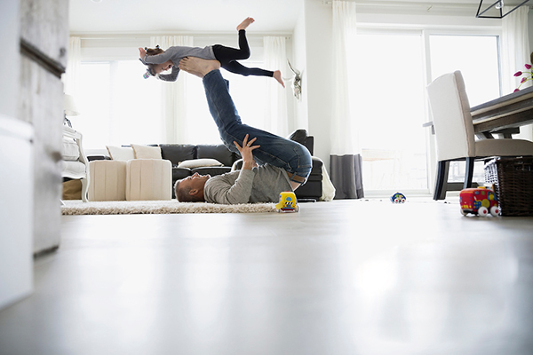 Father flying daughter on feet in living room